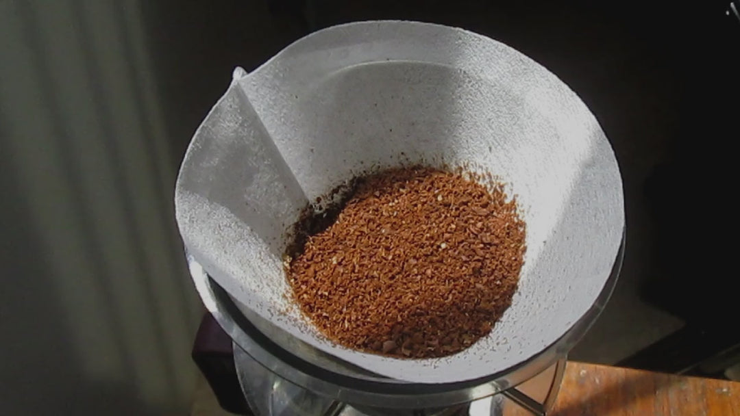 Freshly ground coffee being brewed in a pour-over filter, hot water streaming over grounds to create fresh drip coffee